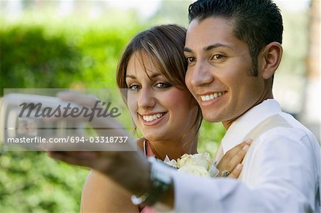 Well-dressed teenage couple taking photograph outside
