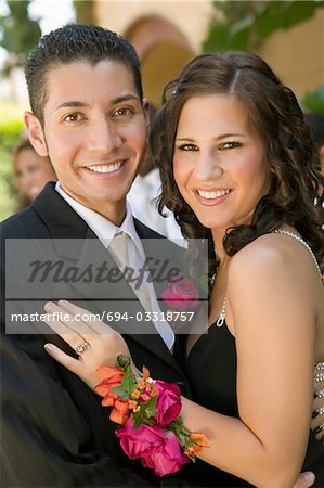 Well-dressed teenage couple embracing outside school dance, portrait