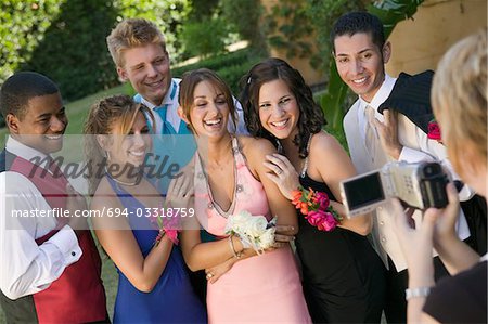 Well-dressed teenagers posing for video camera outside school dance
