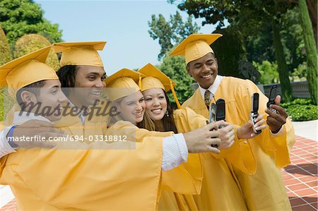 Groupe de diplômés de prendre des photos avec le téléphone cellulaire à l'extérieur