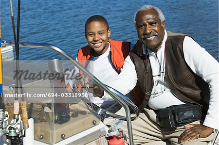 Grandfather and grandson sitting on fishing boat, (portrait)