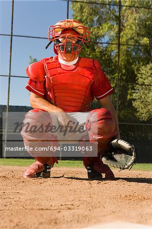 Accroupi sur le terrain de baseball, donnant des signes de la main de baseball