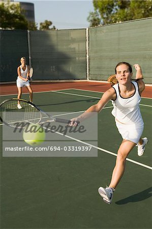 Tennis Player Reaching to hit tennis ball on tennis court