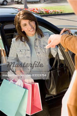 Woman with shopping bags getting out of car, portrait