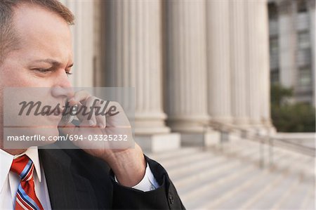 Businessman using mobile phone outside courthouse