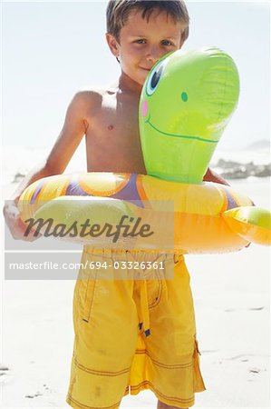 Garçon jouant avec Float Tube sur la plage