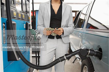 Frau stehend von van mit Kraftstoff Pumpe zählen Geld, Mitte Abschnitt