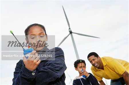 Vater und Kinder (7-9) spielen mit Funkgerät am Windpark