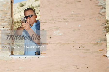 Man aiming hand gun at firing range