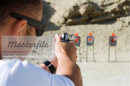 Man aiming hand gun at firing range