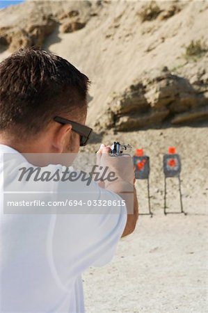 Man aiming hand gun at firing range