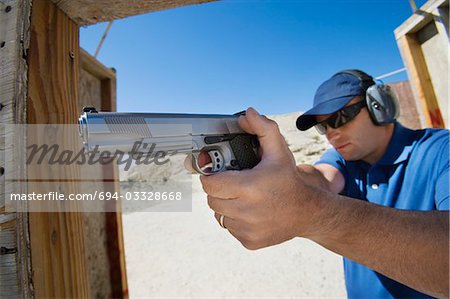 Man aiming hand gun at firing range