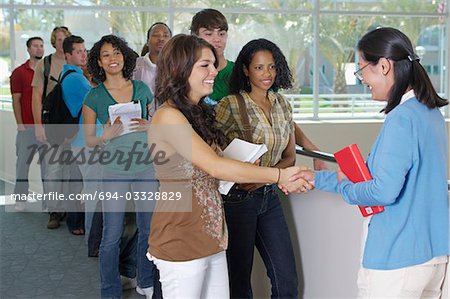 Students shaking hands with teacher on balcony in school