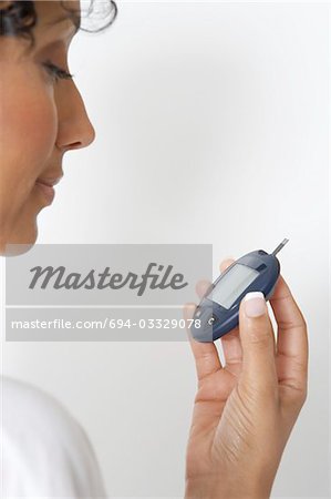 Woman checking diabetes test, close-up, studio shot