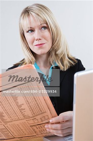 Businesswoman Reading Stock Listings in Newspaper