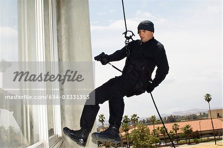 SWAT Team Officer Rappelling and Aiming Gun