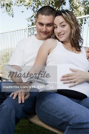 Expectant couple relaxing on bench