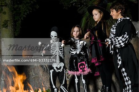 Mädchen und jungen (7-9) tragen Halloween-Kostüme, Eibische am Lagerfeuer Kochen