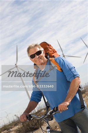 Alter Mann mit Fahrrad in der Nähe von Windparks
