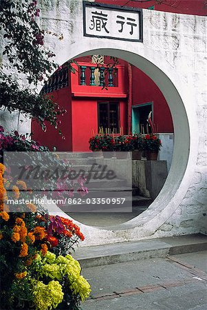 Un arc décoratif traverse un jardin de fleur dans le monastère de Po Lin sur l'île de Lantau, Hong Kong.