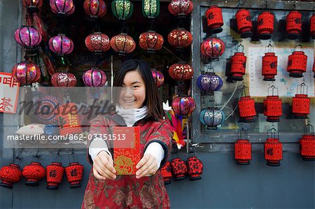 China,Beijing. A Chinese girl wearing traditional Chinese style clothes holding a Hongbao envelope which is received with money by students and children during Chinese New Year Spring Festival .