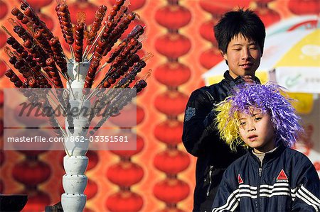 China,Beijing. Chinese New Year Spring Festival - two boys at a hawthorne sweet stand at Longtanhu Park Fair.