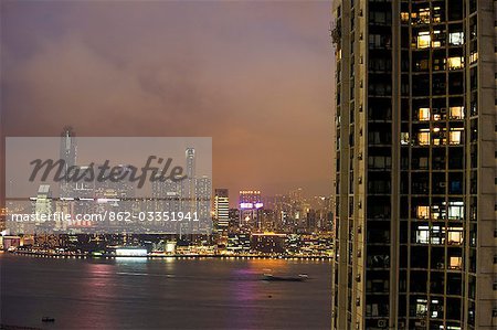 Chine, Hong Kong, Causeway Bay. En regardant à travers l'horizon lumineux de Kowloon de l'île de Hong Kong avec une Star Ferry flou au premier plan.
