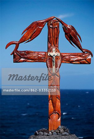 Croix en bois érigé sur la côte sud, combinant le crucifix chrétien avec les emblèmes sculptés des poissons de la mer