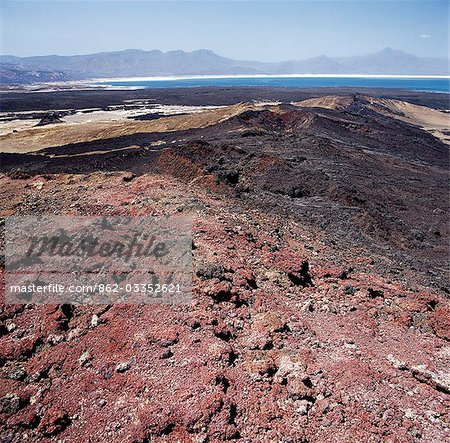 Red volcanic debris from the explosion crater of Garrayto lies on the surface of the hills that divide Lake Assal (in the distance) from the sea.