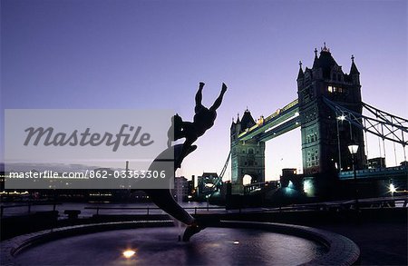 The Dolphin with a Boy statue on the banks of the Thames River beside Tower Bridge in London