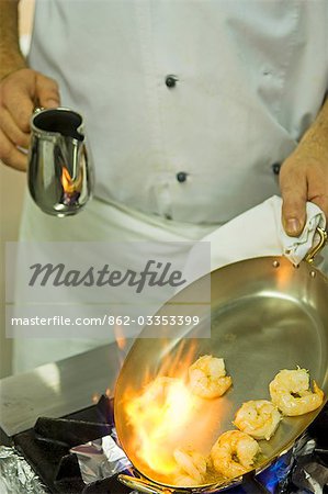 UK,Northern Ireland,Fermanagh,Enniskillen. A chef flambeing prawns in the kitchen at Lough Erne Golf Resort.