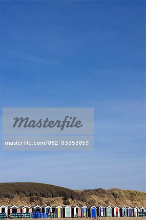 England,Devon. On the north Devon coast at Saunton Sands near Barnstable,a line of mulitcoloured beach huts sits in front a protective sand dune.