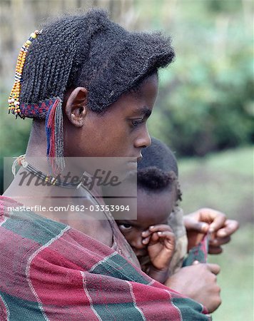A young mother and child of the Arsi-Oromo people west of Aje. Both have unusual hairstyles. The braids falling from the crown of the mother's head have been attractively woven with wool to make a colourful fringe.
