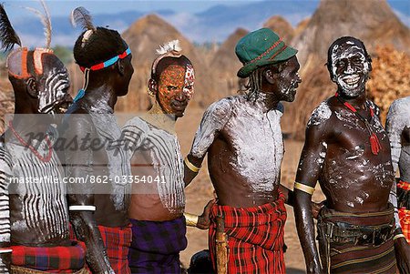At a dance in the Karo village of Duss men stand waiting to dance. A small Omotic tribe related to the Hamar,the Karo live along the banks of the Omo River in southwestern Ethiopia. They are renowned for their elaborate body art using white chalk,crushed rock and other natural pigments.