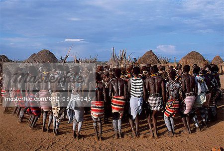 The men hold hands forming a circle within which the women dance in the Karo village of Duss. A small Omotic tribe related to the Hamar,the Karo live along the banks of the Omo River in southwestern Ethiopia. They are renowned for their elaborate body art using white chalk,crushed rock and other natural pigments.