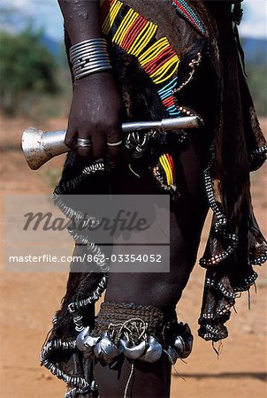 A Hamar woman wears an intricately beaded leather skirt and bells round her legs as well as carrying a tin horn,to the bull-jumping ceremony of her brother,a rite of passage to manhood.