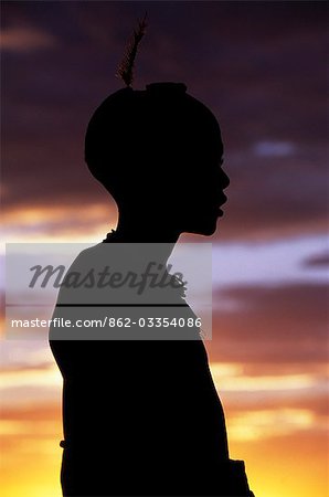 A Dassanech girl leaning against a bale of cattle fodder on a raised platform is silhouetted against the evening sky at a settlement alongside the Omo River. Much the largest of the tribes in the Omo Valley numbering around 50,000,the Dassanech (also known as the Galeb,Changila or Merille) are Nilotic pastoralists and agriculturalists.