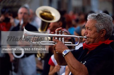 Un trompettiste joue charanga pour accompagner les chefs de plâtre gigantesque qu'elles sont traitées dans les rues de la village de cccccc pendant le festival des géants et présomptueuses (Gigantes y Cabezados)