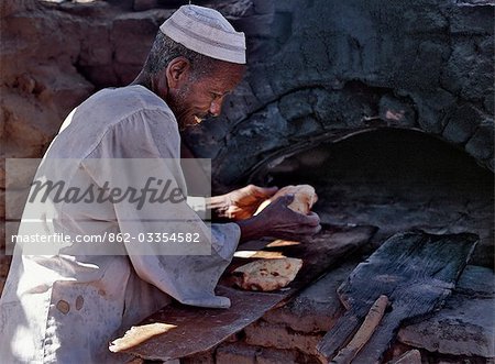 A Nubian baker removes bread from his wood-fired oven.