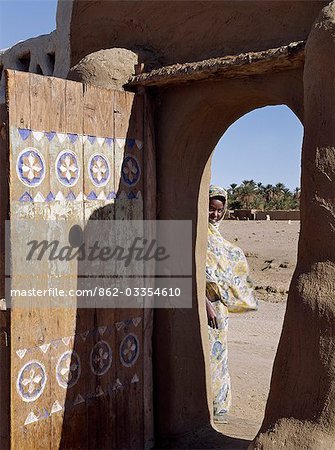 A finely carved painted door graces the arched entrance to a house compound at Qubbat Selim. This village,situated close to the River Nile in Northern Sudan,still retains much of its traditional architecture,plasterwork and decoration..
