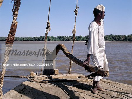 A Nubian boatman at the helm of his felucca,a wooden sailing boat that plies the waters of the River Nile in Egypt and The Sudan.