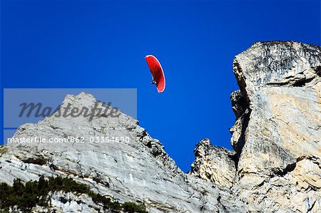 A paraglider sails through high mountains in the Interlaken Valley,Interlaken,Jungfrau Region,Switzerland