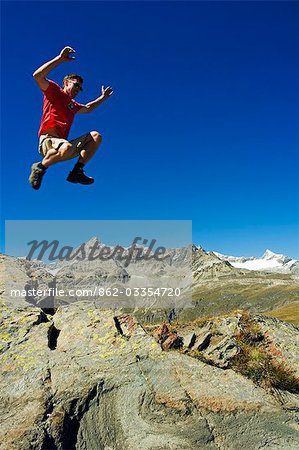 Hiker jumping high on trails at Schwarzee Paradise,Zermatt,Valais,Switzerland Hiker jumping high on trails at Schwarzee Paradise,Zermatt,Valais,Switzerland