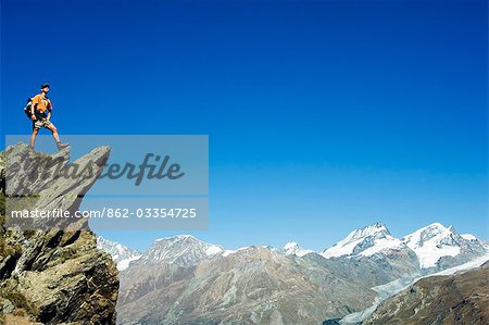 Hiker high on trail above snow capped mountains,Zermatt,Valais,Switzerland Hiker high on trail above snow capped mountains,Zermatt,Valais,Switzerland