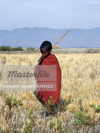 A young boy of the Datoga tribe crosses the plains east of Lake Manyara in Northern Tanzania. The Manyara escarpment (a western boundary wall of the Gregory Rift) is visible in the distance. The Datoga (known to their Maasai neighbours as the Mang'ati and to the Iraqw as Babaraig) live in northern Tanzania and are primarily pastoralists..