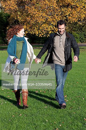 A mid adult couple hold hands in dulwich park