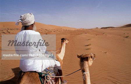 Un Bedu chevauche son chameau dans le désert