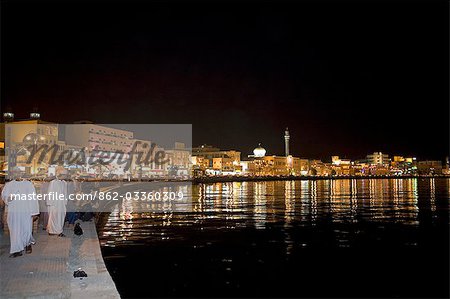 Oman,Muscat. Looking across the water to the brightly lit Corniche and the Mutrah Souq area of the countries capital,a traditional bazar the souq is a warren of alleyways and lined by traditional stalls.