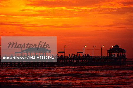 The sun sets over the Pacific,silhouetting figures on the jetty at Huanchaco,on the north coast of Peru