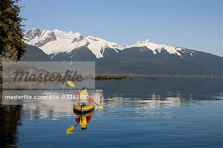 Kayaker paddles the shoreline on a calm afternoon in Lynn Canal just outside Berners Bay in Alaska's Tongass Forest, Inside Passage.